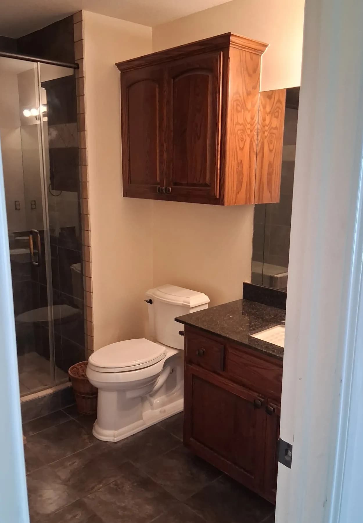 Bathroom with tiled shower, wood vanity, countertop, and tile floor